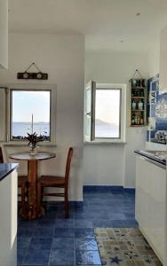 伊斯基亞的住宿－BeachHouse Ischia，厨房配有桌子和桌子以及2扇窗户。