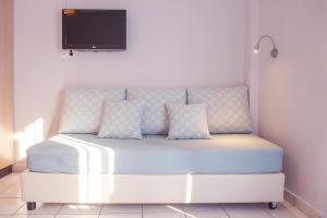 a white bed with pillows and a tv on a wall at Christof Studios in Agia Galini