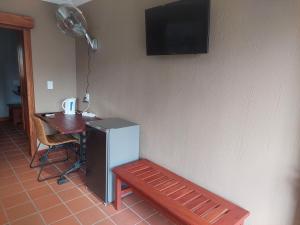 a room with a bench and a table and a television at Allo Allo in Boksburg