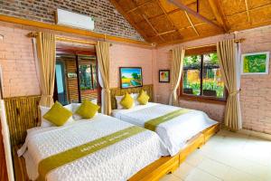 1 Schlafzimmer mit 2 Betten und gelben Kissen in der Unterkunft Green Peace Bungalow in Ninh Bình