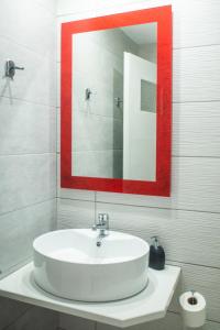 a bathroom with a white sink and a red framed mirror at Christof Studios in Agia Galini