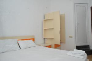 a bedroom with a white bed and a cabinet at Orange Home Hotel in Batumi