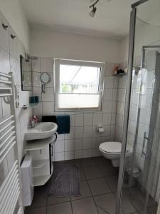 ein Bad mit einem Waschbecken, einem WC und einem Fenster in der Unterkunft Apartement Meerblick in Wunstorf