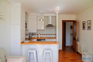 a kitchen with white cabinets and a counter with stools at la cotera vut in Colombres
