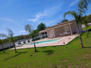 a house with a swimming pool in a field with palm trees at Janus Casa nel Verde - Relax Pool & Spa in Giano Vetusto