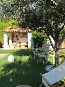 a garden with a table and a ball on the grass at La Maison 1440 in L'Isle-sur-la-Sorgue