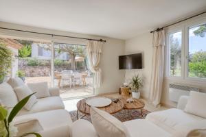 ein Wohnzimmer mit weißen Möbeln und einem Tisch in der Unterkunft Villa des Roses à Lorgues in Lorgues