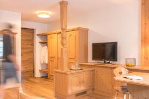a living room with a tv and wooden cabinets at Hotel Gasthof Hirschentenne in Stams