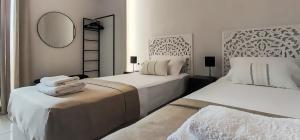 a white bedroom with two beds and a mirror at Niki`s Luxury Apartment in Makry Gialos