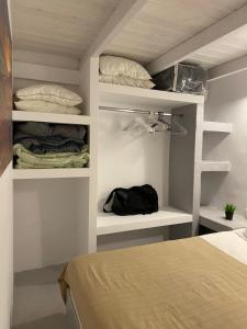 ein Schlafzimmer mit einem Bett sowie weißen Wänden und Regalen in der Unterkunft Villaggio One in Emporio