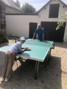 a man and a girl sitting at a ping pong table at Maison d'hôtes La Doucelle culture et bien-être in Lignieres-Orgeres