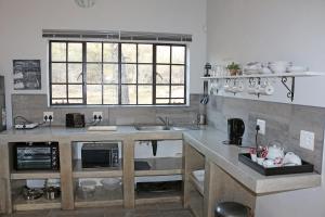 a kitchen with a counter with a sink and a window at Villa de Leeu, Perfect for Two in Marloth Park
