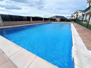 a large blue swimming pool in front of a house at APARTAMENTO PLAYA CATEDRALES CON PISCINA Y TERRAZA in Barreiros