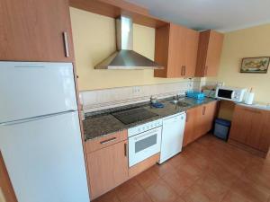 a kitchen with a white refrigerator and a sink at APARTAMENTO PLAYA CATEDRALES CON PISCINA Y TERRAZA in Barreiros