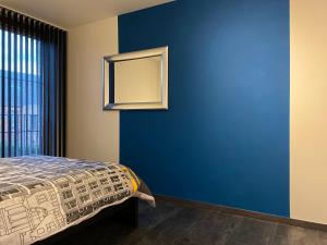 Un dormitorio con una pared azul y una cama en Casper House, Near Maastricht, en Lanaken