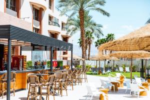 un patio extérieur avec des tables, des chaises et des parasols dans l'établissement Jacob Eilat, à Eilat