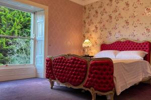 a bedroom with a red bed and a window at Annsborough House Castlewellan in Castlewellan