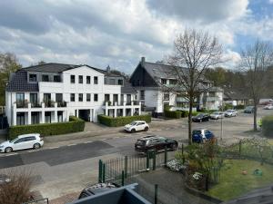 un grand bâtiment blanc avec des voitures garées dans la rue dans l'établissement FeWo Ruhrnatur „Modern trifft Gemütlichkeit“, à Mülheim