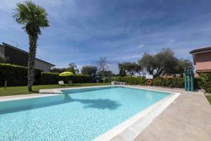 una piscina in un cortile con una palma di La Palma - Immobiliare Azzurra a Lazise