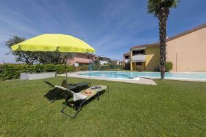 un ombrellone giallo seduto sull'erba accanto a una piscina di La Palma - Immobiliare Azzurra a Lazise