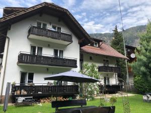 a white house with an umbrella in front of it at Appartement Sonnenstrahl Ferienhaus Fuenf Sinne in Döbriach