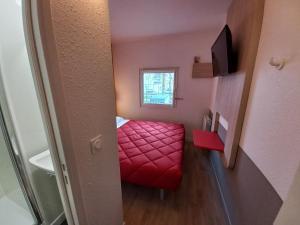 um pequeno quarto com um repousa-pés vermelho e uma janela em Premiere Classe Evry Sud - Mennecy em Ormoy