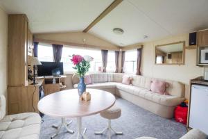sala de estar con sofá y mesa en Lovely 6 Berth Caravan At Naze Marine Holiday Park In Essex Ref 17003c, en Walton-on-the-Naze