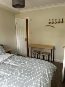 a bedroom with a bed and a table with two stools at Private room in family home in Iford