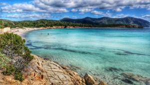 una vista di una spiaggia con persone in acqua di Da Miky Casa Vacanze Teulada Sud Sardegna a Teulada
