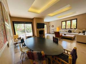 sala de estar con mesa y sofá en Villa Hanaa sur golf piscine privée, en Marrakech