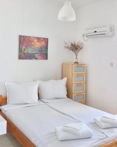 1 cama con sábanas blancas y almohadas blancas en 4 Ambelia paradise, en Megalochori