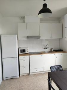 uma cozinha branca com armários brancos e uma mesa em Apartamento vacacional en Playa del Vao - Corujo em Vigo