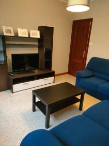 uma sala de estar com um sofá azul e uma mesa de centro em Apartamento vacacional en Playa del Vao - Corujo em Vigo
