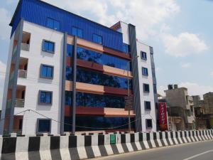 ein großes Gebäude mit blauen Fenstern auf einer Stadtstraße in der Unterkunft Vaidehi Inn-A Unit of vaidehi guest house in Deoghar
