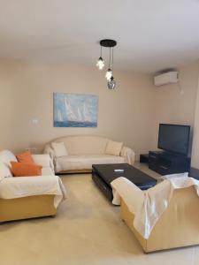 een woonkamer met 2 banken en een tv bij Marina Apartment in Sarandë