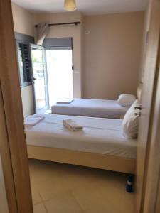 twee bedden in een kamer met een raam bij Marina Apartment in Sarandë