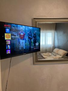 einen Flachbild-TV, der an einer Wand neben einem Spiegel hängt in der Unterkunft Home Chiara in Bari