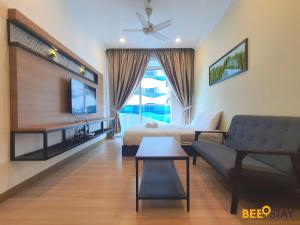 a living room with a bed and a couch and a tv at The Wave Suites Melaka by BEESTAY in Melaka