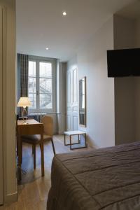 a hotel room with a bed and a desk with a lamp at Hotel du Th&eacute;atre in Lyon
