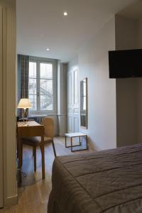 a hotel room with a bed and a desk with a lamp at Hotel du Théatre in Lyon