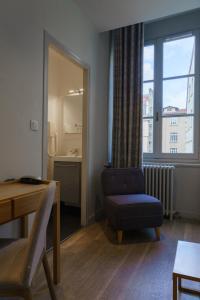 Habitación con silla, mesa y espejo. en Hotel du Théatre, en Lyon