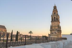 un edificio con una torre de reloj junto a una valla en Hotel Marisa en Córdoba