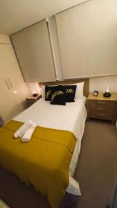 um quarto com uma cama grande e um cobertor amarelo em Shoreditch & Liverpool Steet Room A em Londres