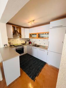 a kitchen with white cabinets and a black rug at Ani Apartments in Umag