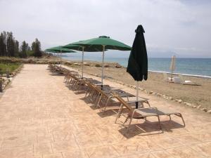 a row of chairs and umbrellas on a beach at Villa Saraliana Sandy Beach Villas - Heated Pool - Jacuzzi - Private Beach Area in Polis Chrysochous
