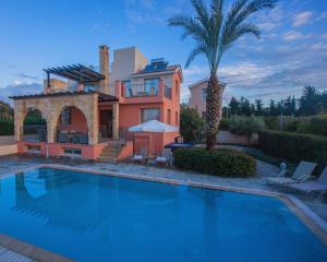 une maison avec une piscine et un palmier dans l'établissement Villa Saraliana Sandy Beach Villas - Heated Pool - Jacuzzi - Private Beach Area, à Pólis Chrysochoús