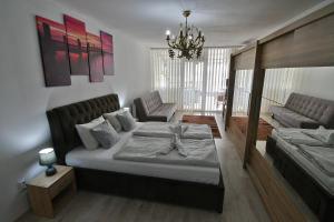 ein Schlafzimmer mit einem Bett, einem Sofa und einem Kronleuchter in der Unterkunft Apartmany Zemplinska Širava Timea in Kaluža