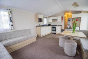a living room with a couch and a table at Modern Caravan With Wifi At Martello Beach Holiday Park In Essex Ref 29015sv in Clacton-on-Sea
