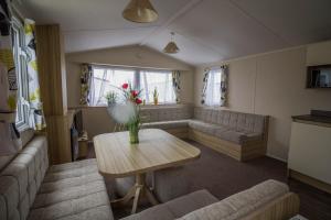 a living room with a table and a couch at Modern Caravan With Wifi At Martello Beach Holiday Park In Essex Ref 29015sv in Clacton-on-Sea