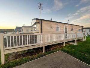 a mobile home with a white fence and a deck at Modern Caravan With Wifi At Martello Beach Holiday Park In Essex Ref 29015sv in Clacton-on-Sea